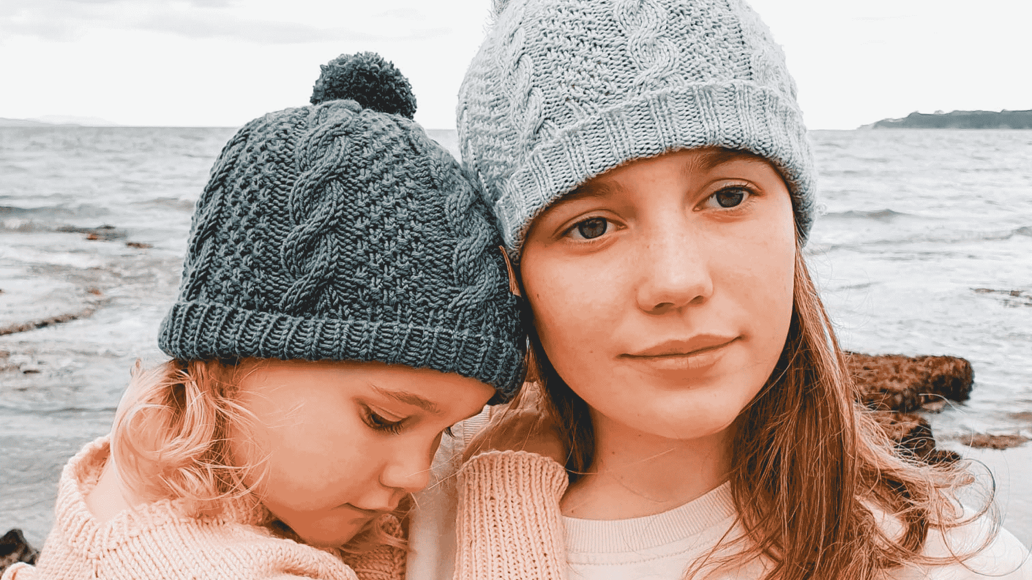 Hand Knitted Cable Beanie in Grey Merino Wool with Pompoms worn by two girls